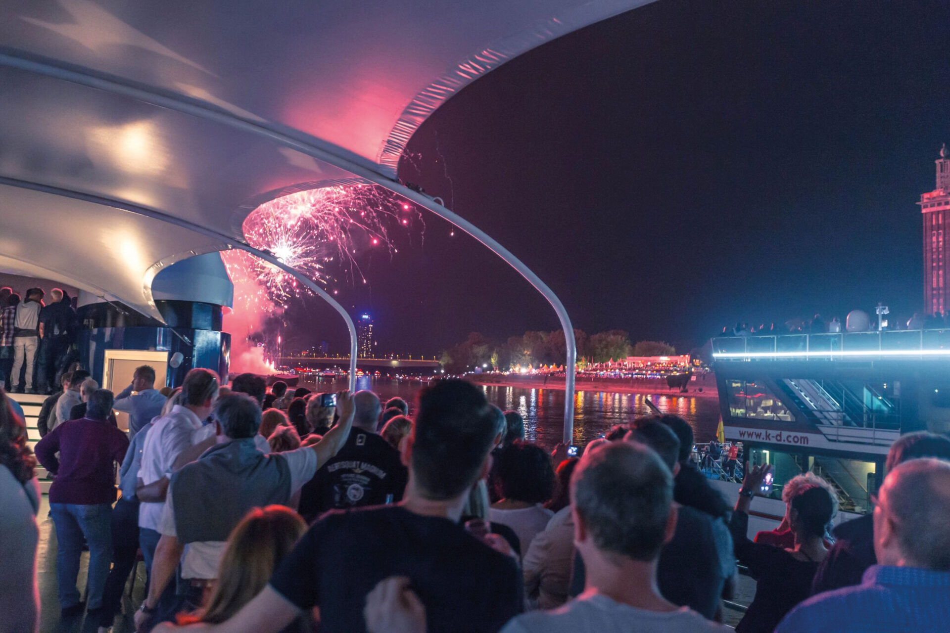 Feierende Menschen auf dem Schiff bestaunen das Feuerwerk
