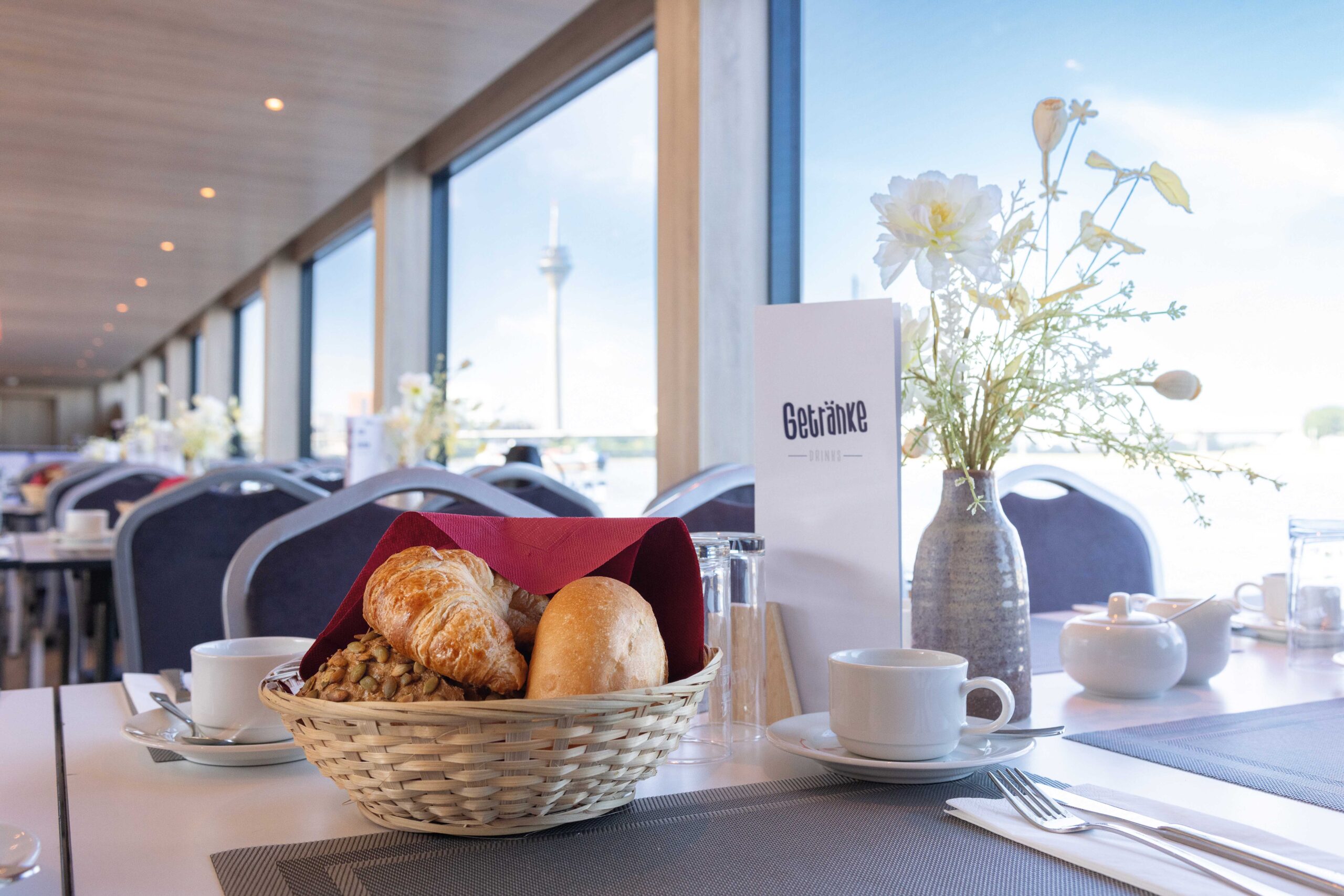 Mit Brötchen und Kaffee eingedeckter Tisch mit Sicht auf den Rhein in Düsseldorf