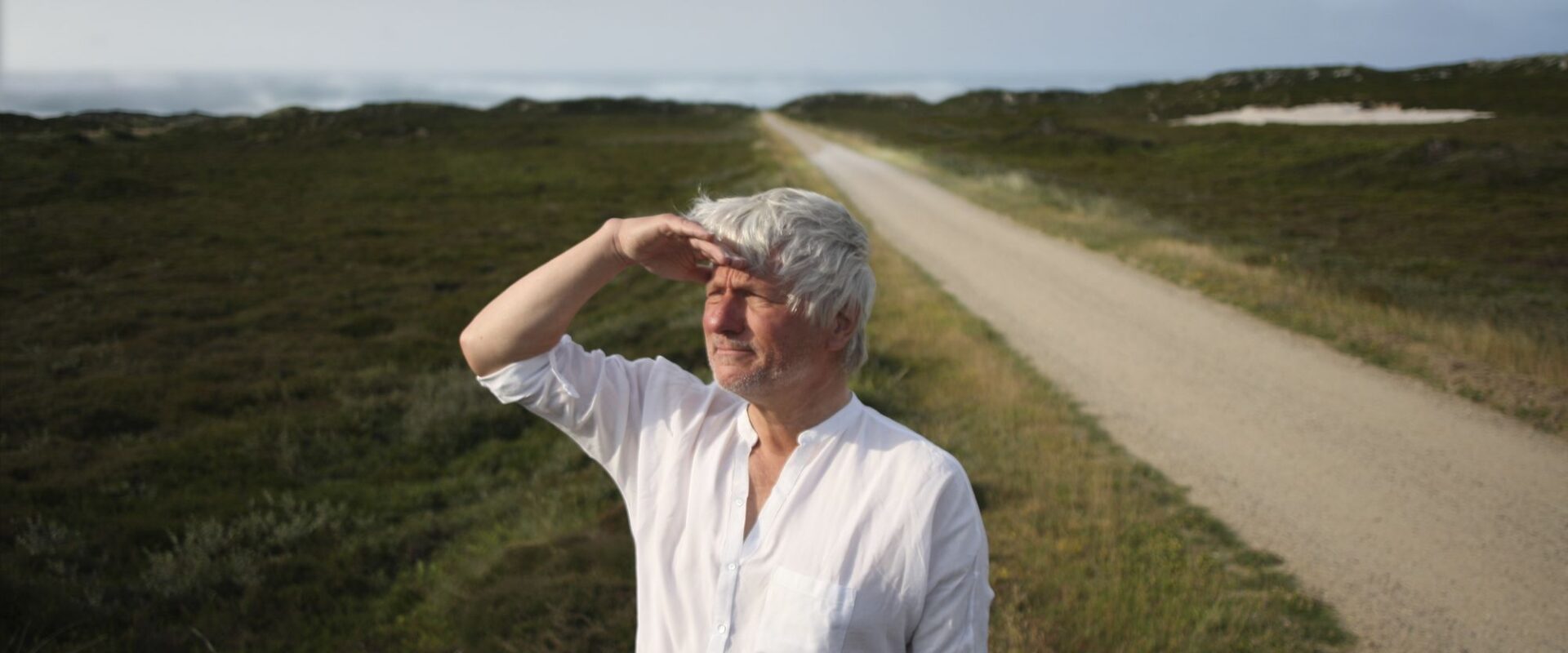 Jürgen Becker schaut auf einem Feldweg in die Ferne