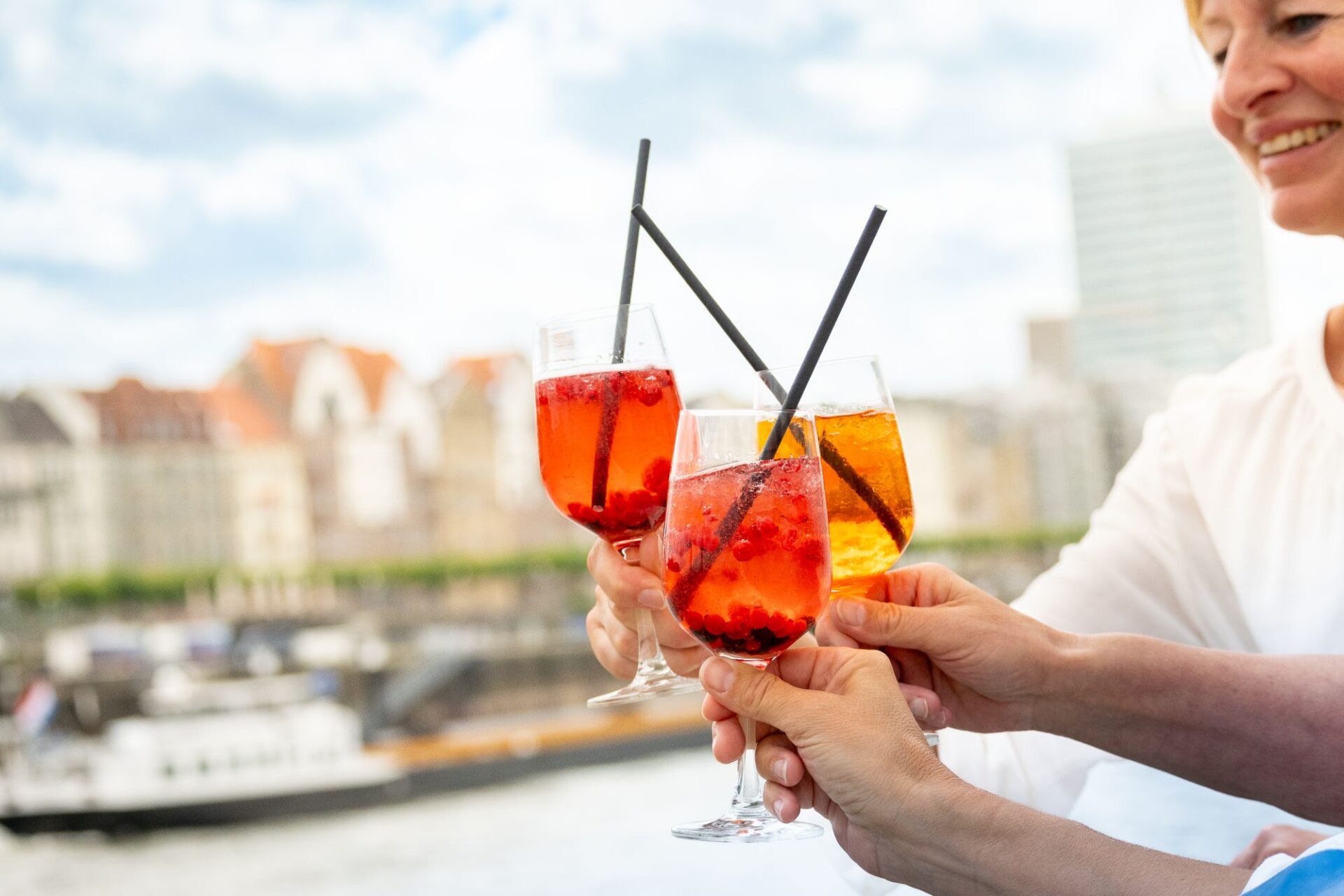 Lounge Abendfahrt Düsseldorf. Mehrere Frauen stoßen am Freideck mit Aperol Spritz an.