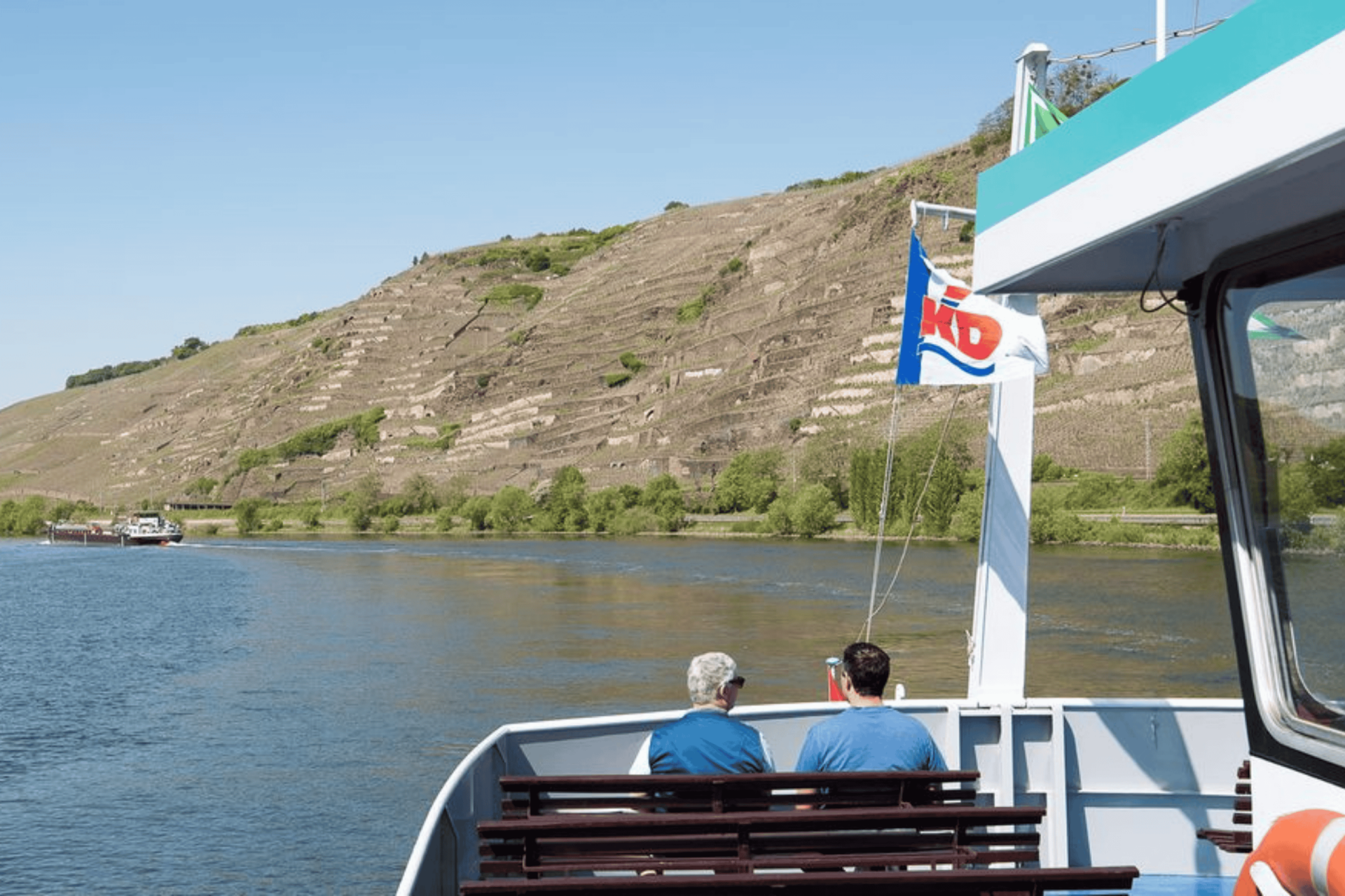 MS Goethe auf dem Mittelrhein. Zwei Männer sitzen hinten am Heck auf einer Bank - zu sehen sind deren Rücken