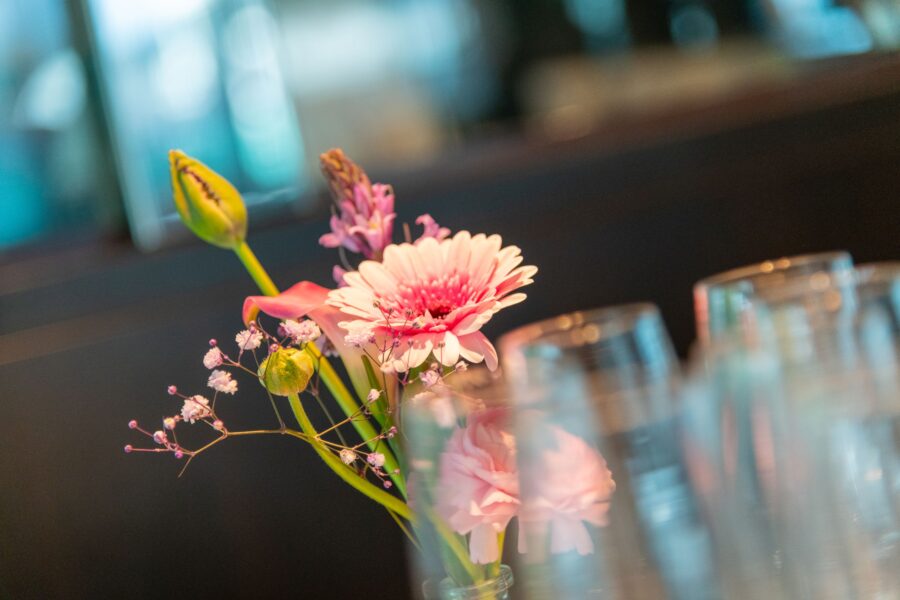 Blumengesteck in der Vase vor Sektgläsern