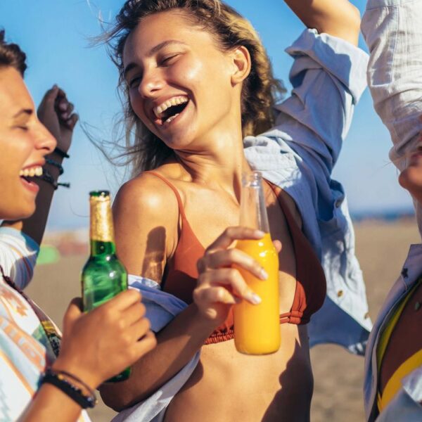 Three women in a good mood on the beach with drinks in hand.