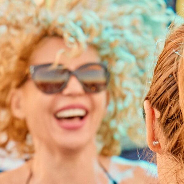 View of the back of a woman's head as she laughs at another woman. The other woman's laughter is clearly recognizable.