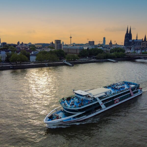 MS RheinFantasie on the Rhine in Cologne at sunset, with the cathedral and the old town promenade in the background