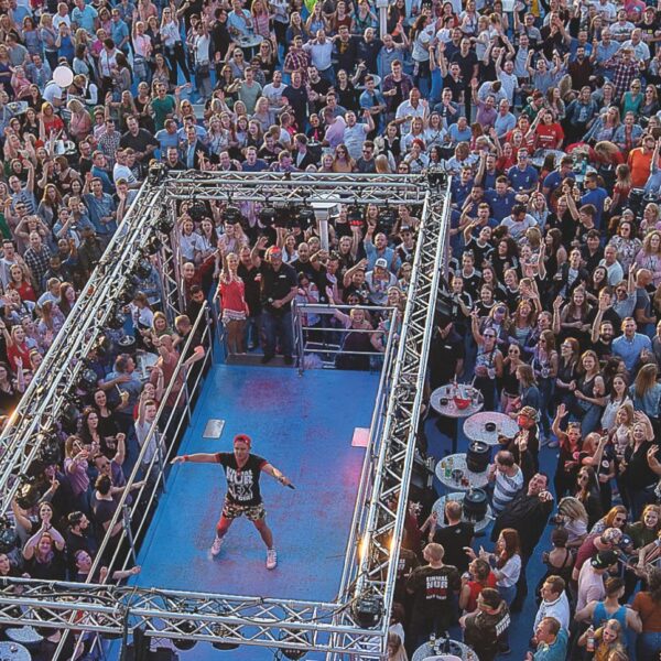 Bird's eye view of the open deck of the RheinFantasie. An entertainer is standing in the middle, surrounded by lots of people enjoying the party