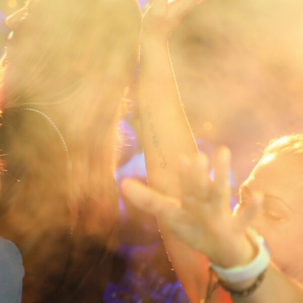 Two women dancing in a crowd are illuminated by the spotlights