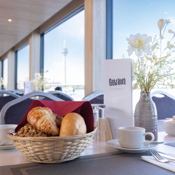 Mit Brötchen und Kaffee eingedeckter Tisch mit Sicht auf den Rhein in Düsseldorf