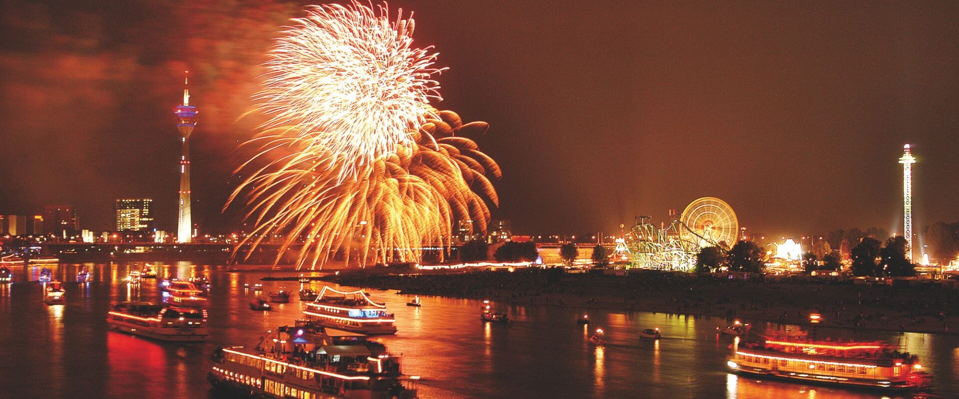 Rhein mit Schiffen und Feuerwerk, im Hintergrund die Kirmes in Düsseldorf bei Nacht