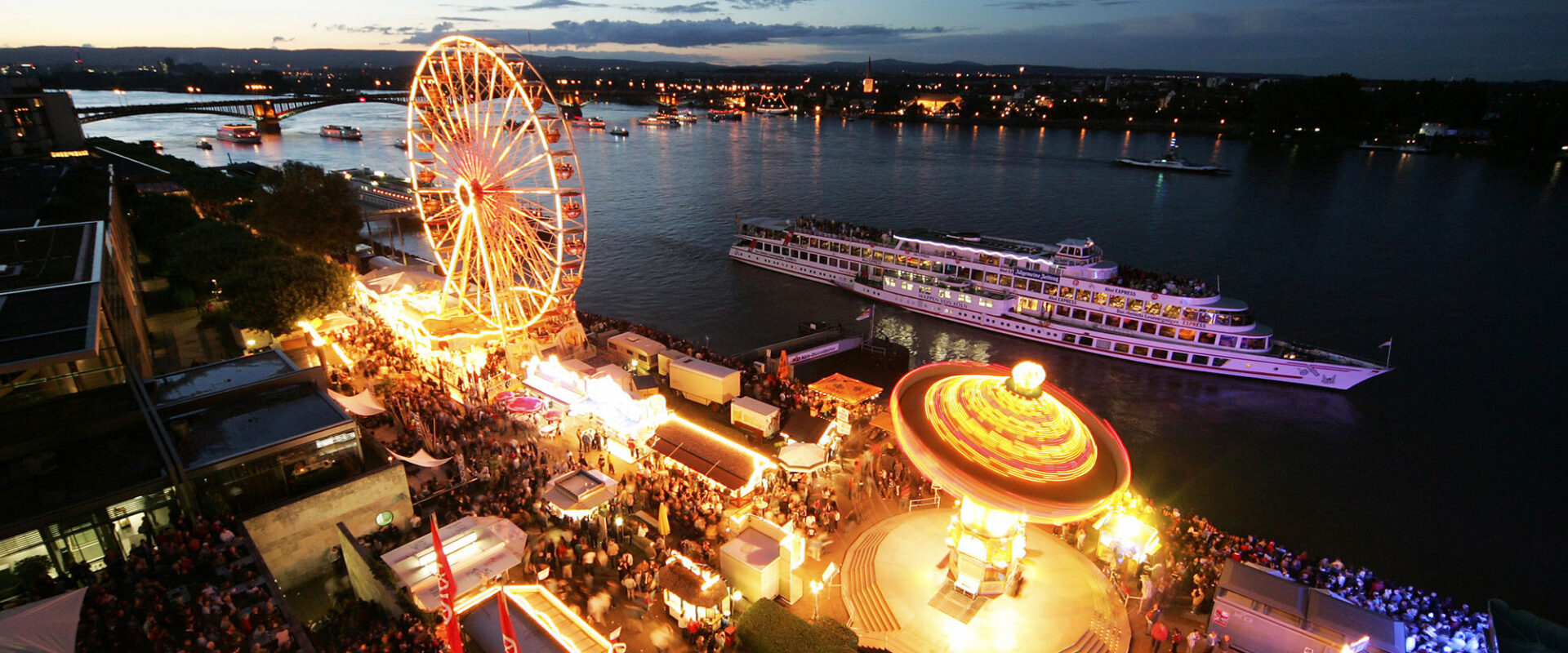Mainzer Johannisnacht mit beleuchteter Kirmes und dem Rhein mit Schiffen dahinter