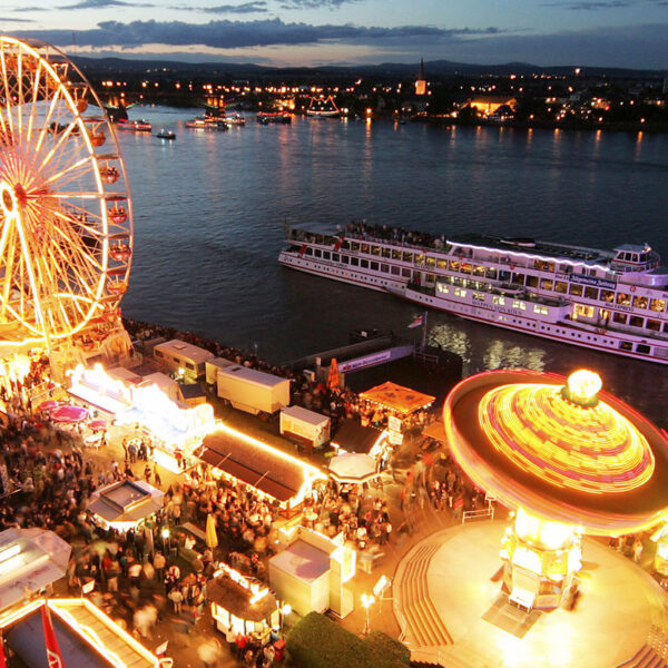 Mainzer Johannisnacht mit beleuchteter Kirmes und dem Rhein mit Schiffen dahinter