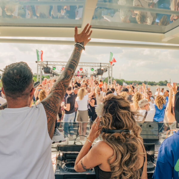 Zwei DJS und eine Djane an den Turntables sprechen zur feierenden Menge