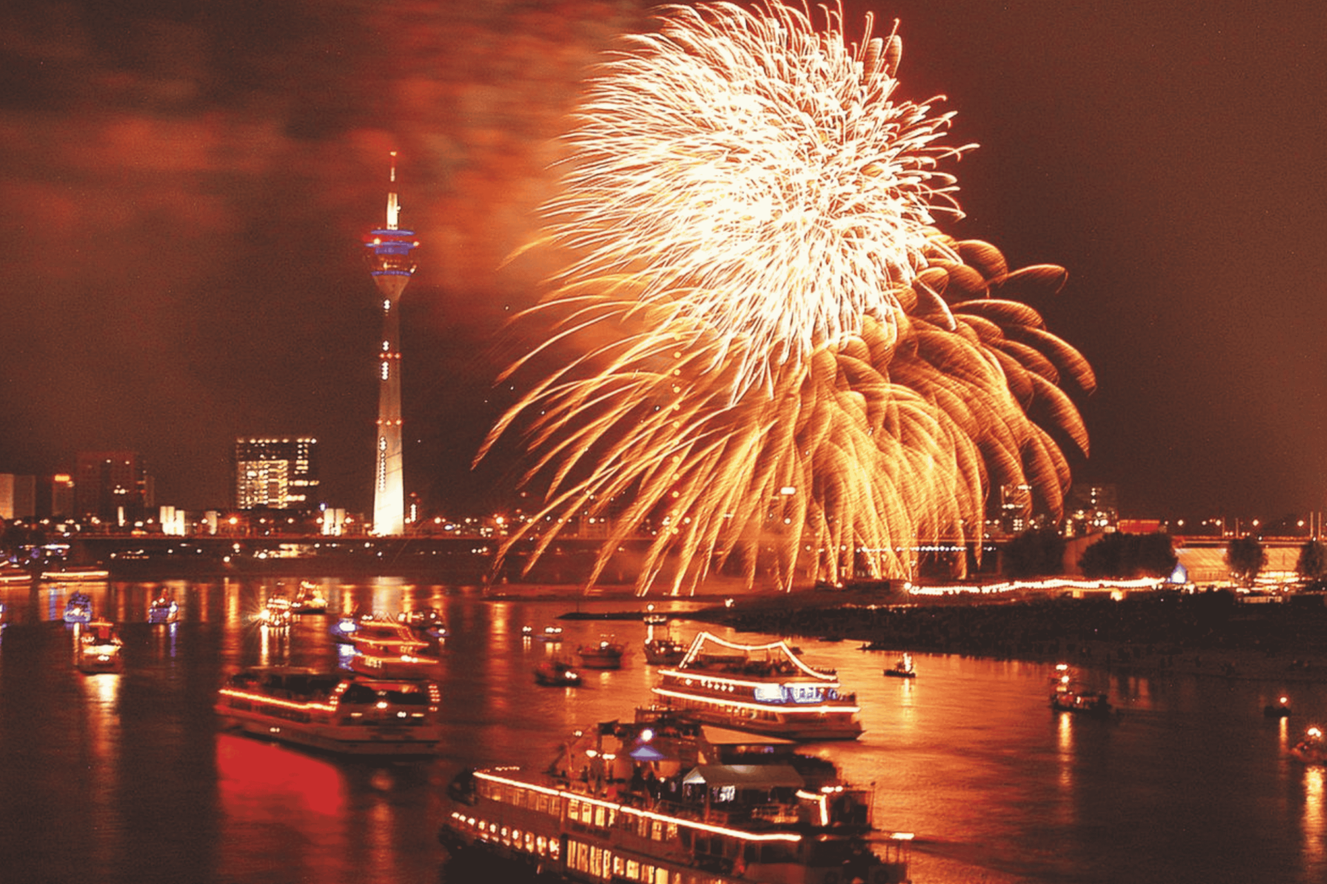 Schiffe auf dem Rhein in Düsseldorf im Dunklen vor Feuerwerk